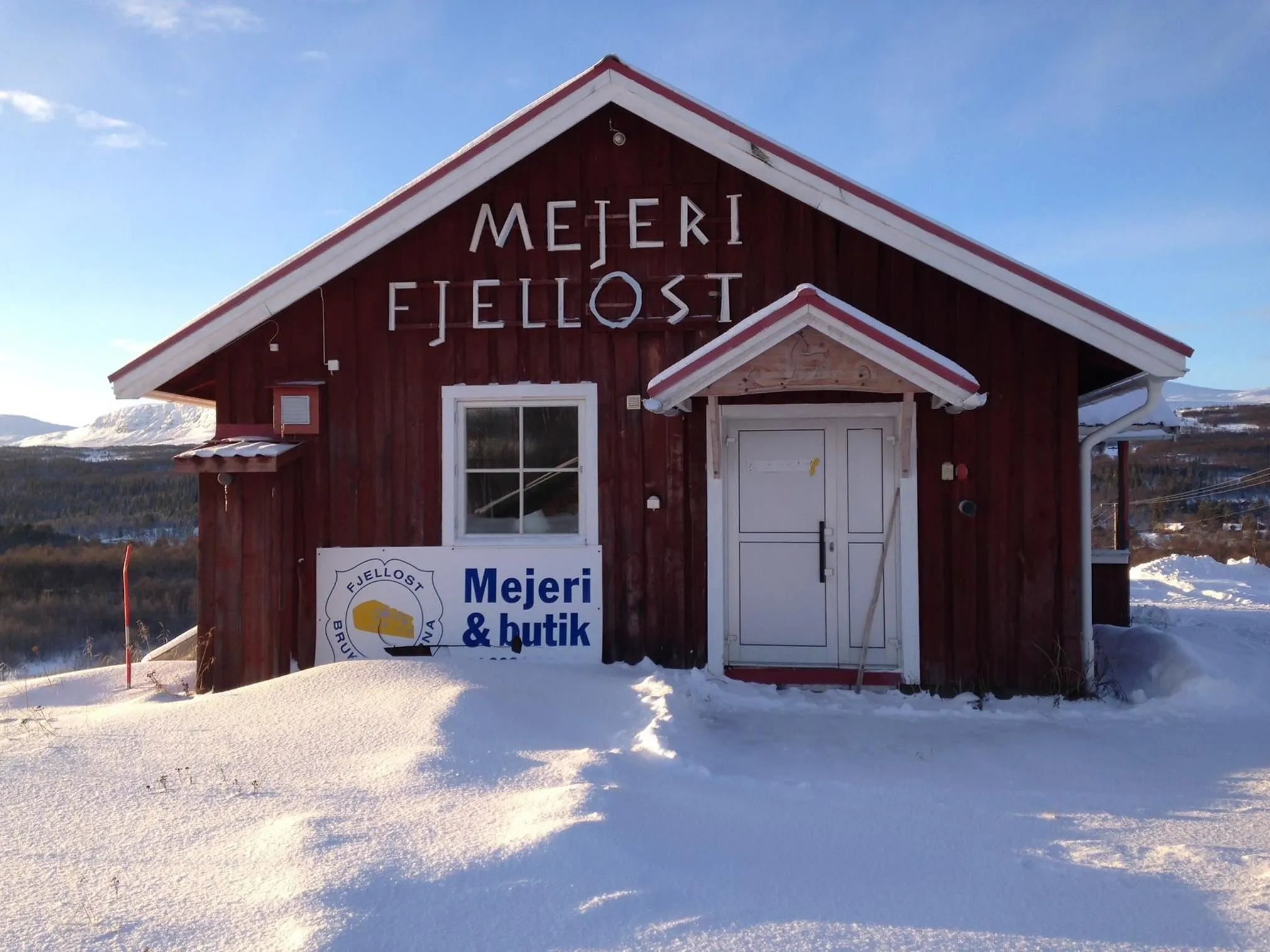 Rött hus med texten "Mejeri Fjellost", på väggen..
