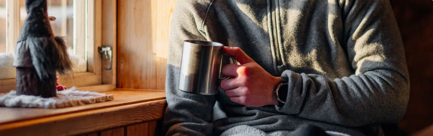 Person dricker kaffe i en våffelstuga på fjället