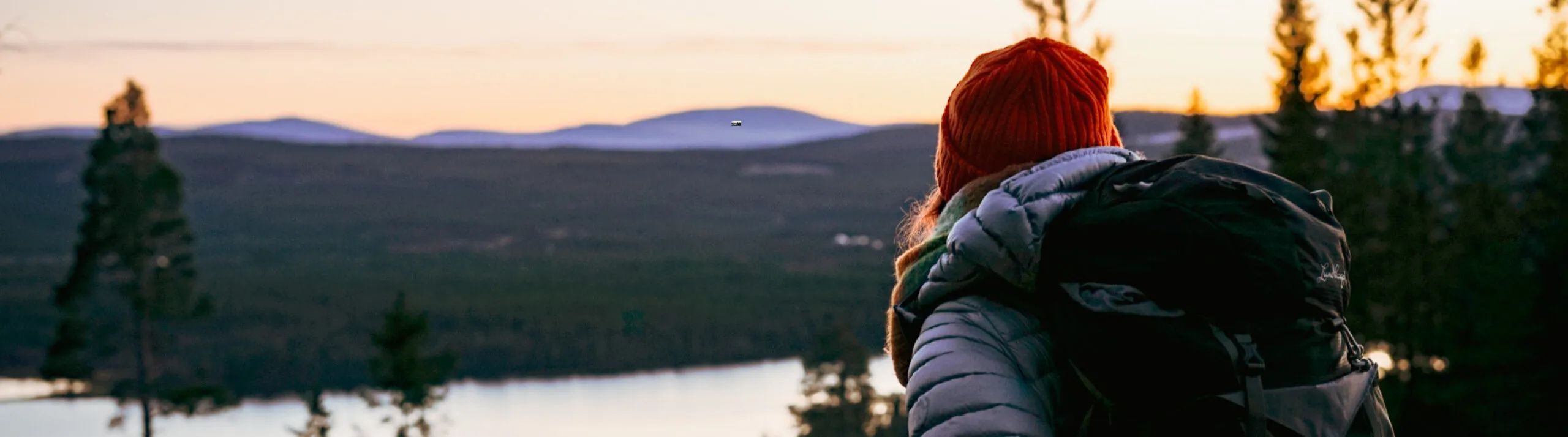 Kvinna blickar ut mot fjäll i skymning