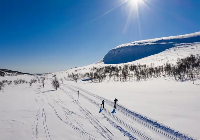 Två personer åker längdskidor i fjällmiljö