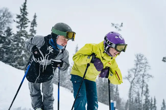 Pojke och flicka står på skidor och kollar nedåt