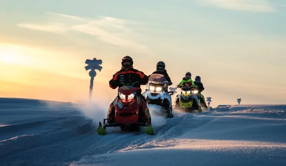 Fyra skoteråkare på fjället i solnedgång.