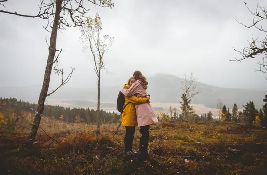 Två tjejer kramas på ett berg