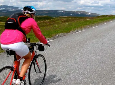 Kvinna cyklar på landsväg i norge
