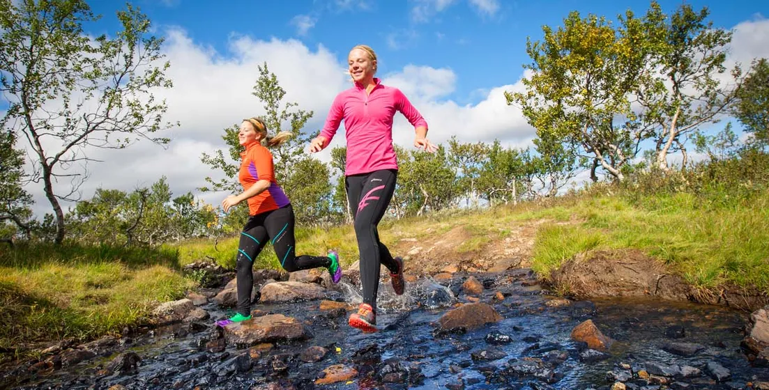 Två kvinnor springer på fjället