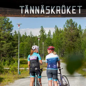Cyklister på väg mot Tännäskröket - de står framför den stora träportalen