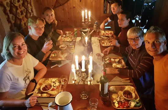 Ett sällskap sitter runt ett bord och äter i skenet från levande ljus.