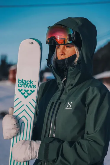 Kvinna står med sina alpinskidor